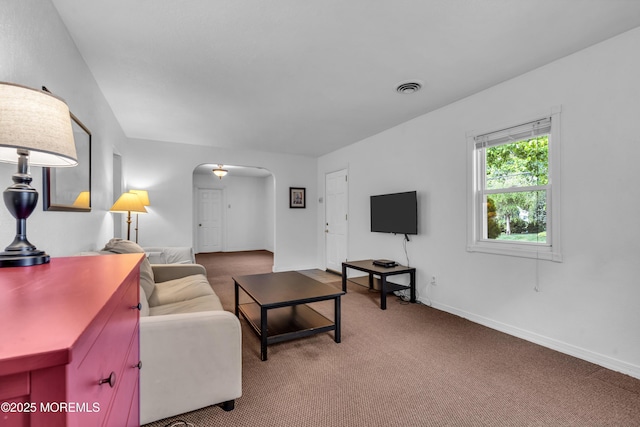 carpeted living room with arched walkways and baseboards