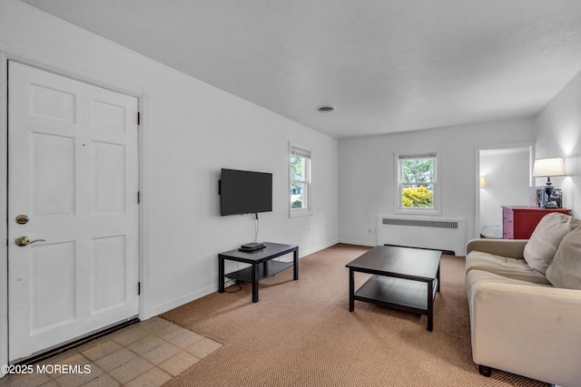living room featuring radiator, light carpet, and baseboards