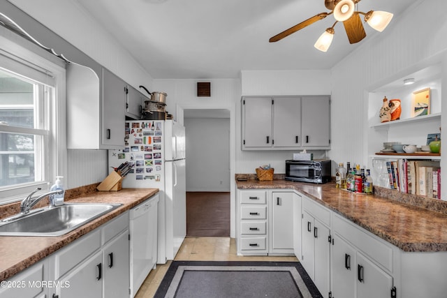 kitchen with a sink, white appliances, ceiling fan, and inlaid floor details