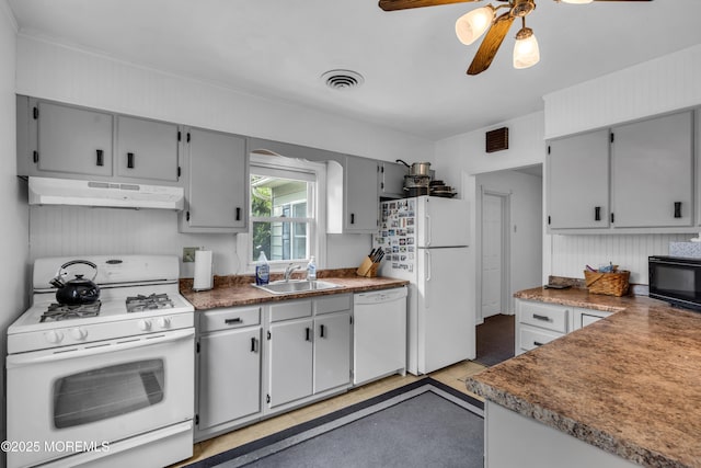 kitchen featuring white appliances, under cabinet range hood, a sink, and gray cabinets