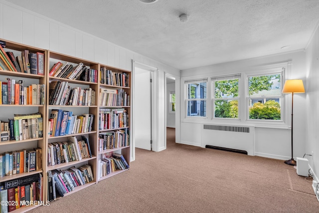living area featuring radiator heating unit, carpet, a textured ceiling, and ornamental molding