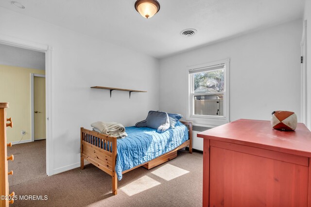 bedroom with radiator heating unit, light colored carpet, and baseboards