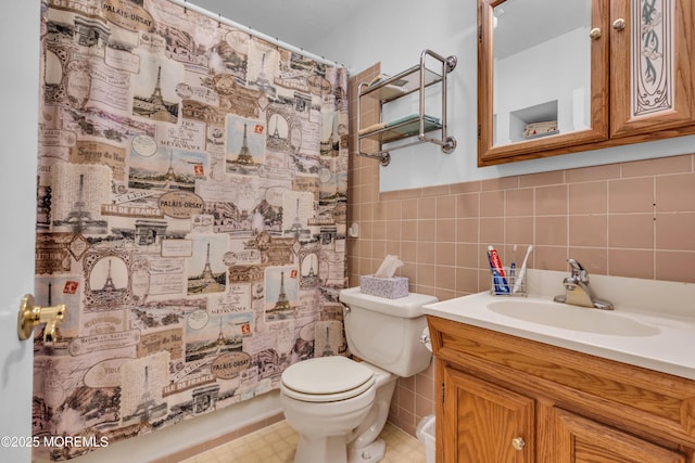 bathroom with tile walls, toilet, vanity, a shower with shower curtain, and wainscoting