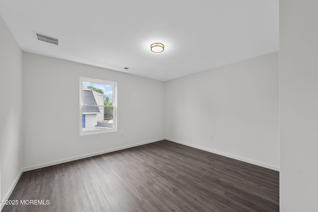 spare room featuring dark wood finished floors and baseboards