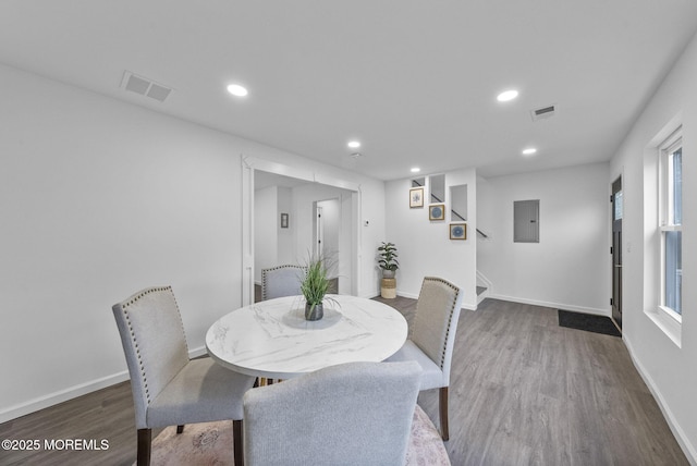 dining room featuring wood finished floors, baseboards, recessed lighting, stairway, and electric panel
