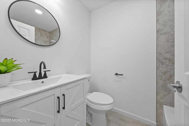 bathroom with toilet, vanity, tile patterned flooring, baseboards, and a bath