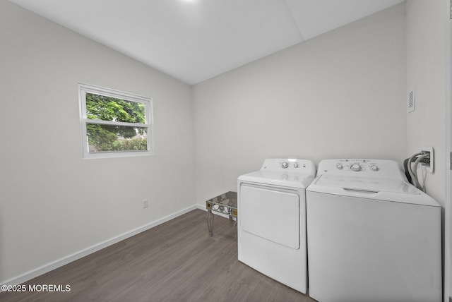 clothes washing area with independent washer and dryer, dark wood-type flooring, and baseboards