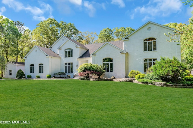 view of front of property with a front yard, roof with shingles, and stucco siding