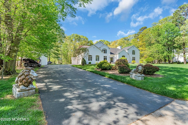 view of front of property featuring driveway, a front yard, and a chimney