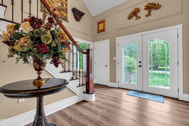 foyer with stairway, wood finished floors, healthy amount of natural light, french doors, and high vaulted ceiling