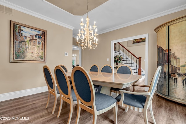 dining room featuring wood finished floors, a chandelier, stairs, ornamental molding, and baseboards