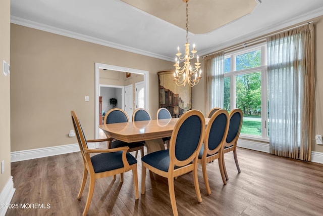 dining room featuring a chandelier, ornamental molding, wood finished floors, and baseboards