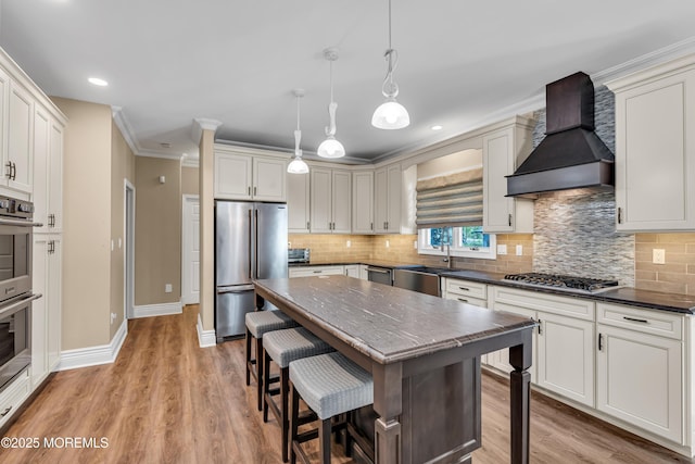 kitchen featuring stainless steel appliances, custom range hood, a sink, baseboards, and a breakfast bar area