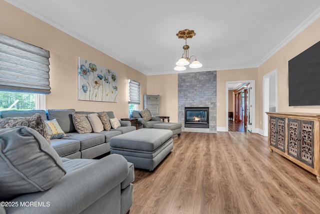living room with ornamental molding, a fireplace, light wood-style floors, and baseboards