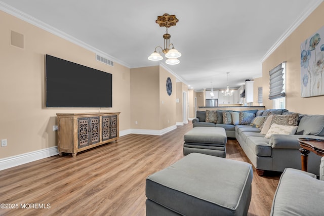 living room featuring a chandelier, ornamental molding, baseboards, and light wood-style floors