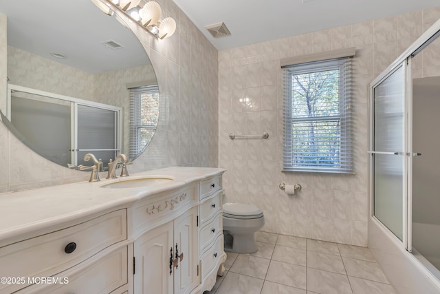 bathroom with tile walls, tile patterned flooring, toilet, and vanity