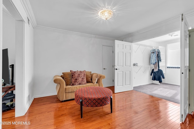 sitting room with light wood-style flooring, ornamental molding, and baseboards
