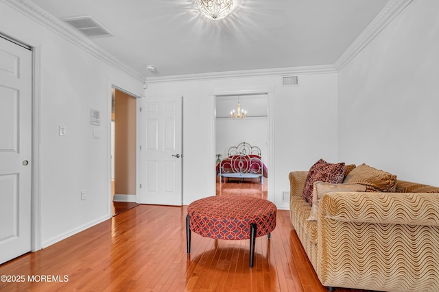 sitting room with a chandelier, wood-type flooring, ornamental molding, and baseboards