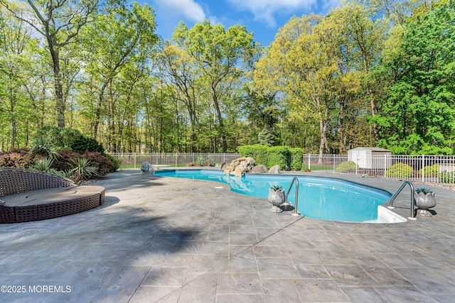 view of swimming pool with fence, a patio area, and an outbuilding
