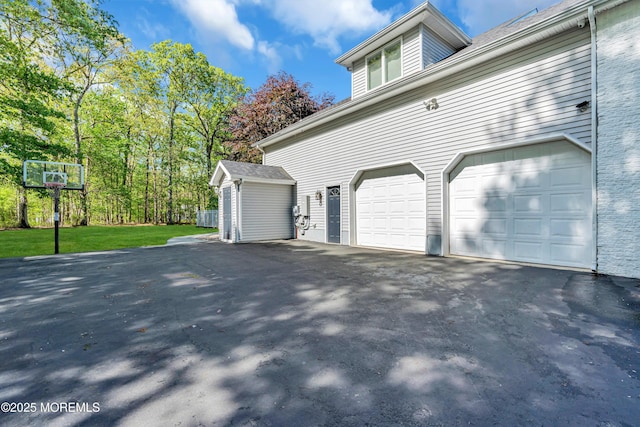 view of side of home featuring asphalt driveway, a garage, and an outdoor structure