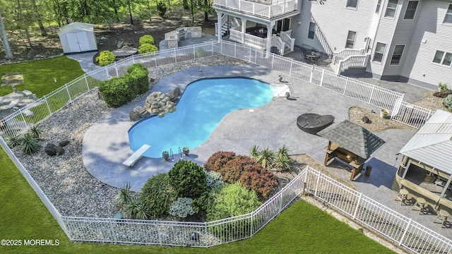 view of pool featuring a diving board, a shed, an outbuilding, and a patio