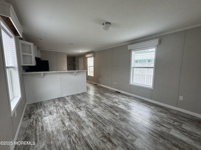 unfurnished living room featuring dark wood-style flooring, crown molding, baseboards, and a textured ceiling