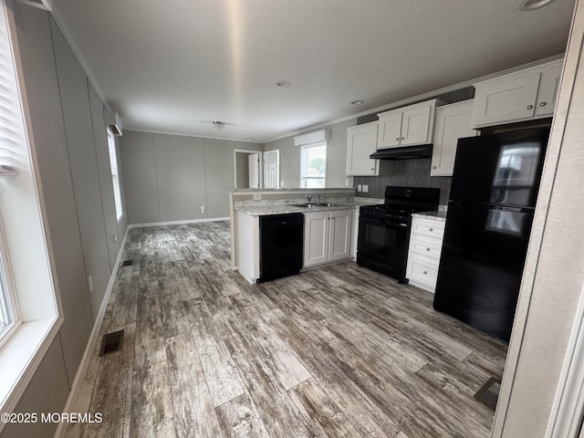 kitchen featuring black appliances, a sink, a peninsula, dark wood-style flooring, and white cabinetry
