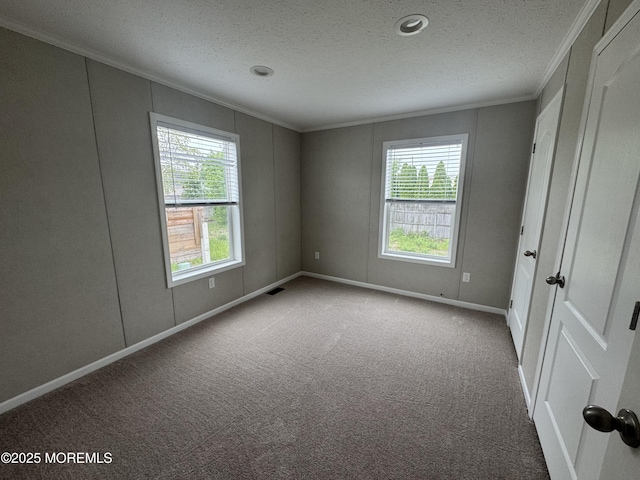 unfurnished bedroom with crown molding, multiple windows, carpet, baseboards, and a textured ceiling