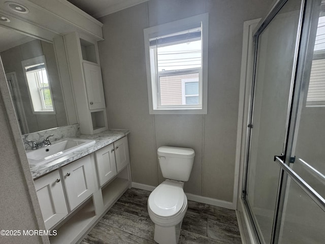bathroom with a shower stall, toilet, vanity, baseboards, and wood finished floors