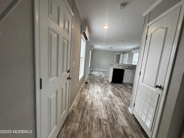 hallway featuring dark wood-style floors, healthy amount of natural light, crown molding, a sink, and recessed lighting