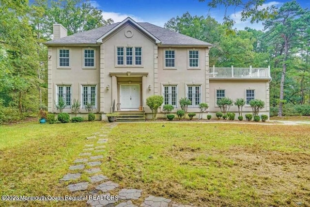 2557 Huckleberry Rd, Manchester, NJ 08759 - view of front of house featuring stucco siding, a chimney, a front lawn, and a balcony