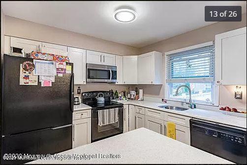 kitchen featuring black appliances, a sink, white cabinetry, and light countertops