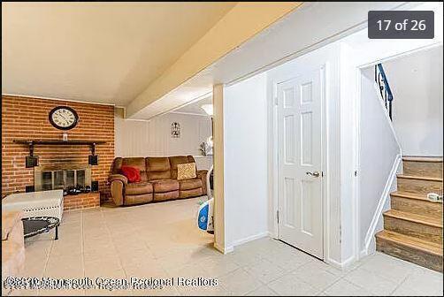living area with stairs, a fireplace, brick wall, and baseboards