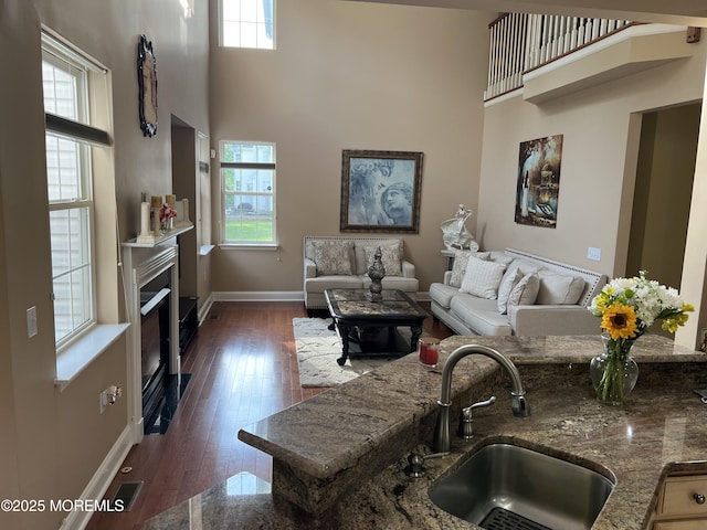 27 Stonehenge Ct, Jackson, NJ 08527 - living room featuring baseboards, a towering ceiling, a fireplace with flush hearth, and dark wood-style floors