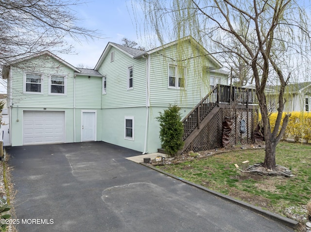 view of front of property featuring asphalt driveway, an attached garage, stairway, a deck, and stucco siding