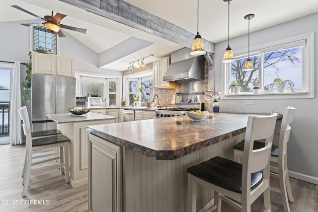 kitchen with appliances with stainless steel finishes, a peninsula, light wood-type flooring, tasteful backsplash, and a kitchen breakfast bar