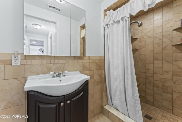 full bath featuring a shower stall, tile walls, vanity, and a wainscoted wall