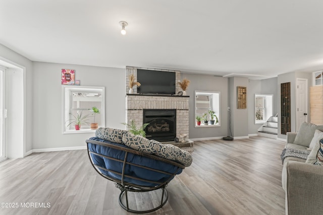 living area with wood finished floors, a fireplace, stairway, and baseboards