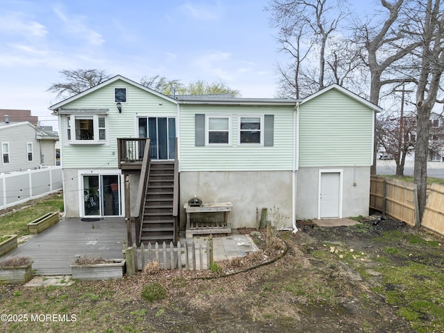 rear view of house with a wooden deck, a fenced backyard, and stairs