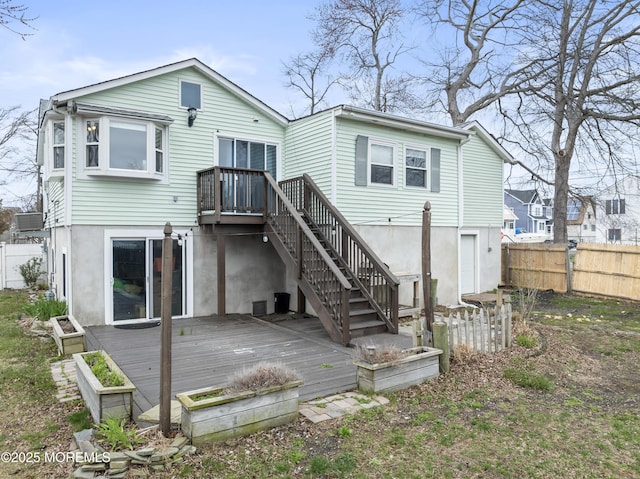 back of house with a deck, fence, and stairway