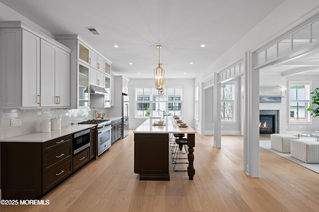 2113 River Rd, Point Pleasant, NJ 08742 - kitchen featuring high end appliances, light countertops, light wood-style floors, a breakfast bar area, and recessed lighting