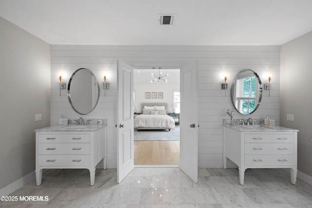2113 River Rd, Point Pleasant, NJ 08742 - ensuite bathroom featuring two vanities, a chandelier, marble look tiles, and baseboards