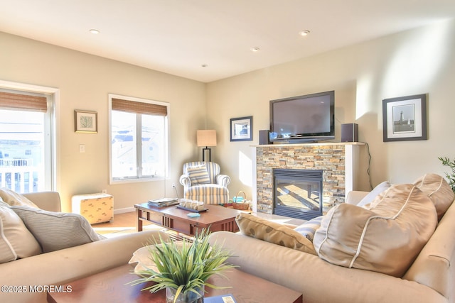 living room with healthy amount of natural light, a stone fireplace, wood finished floors, baseboards, and recessed lighting