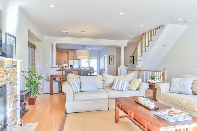 living room with a fireplace, light wood-style flooring, decorative columns, and recessed lighting