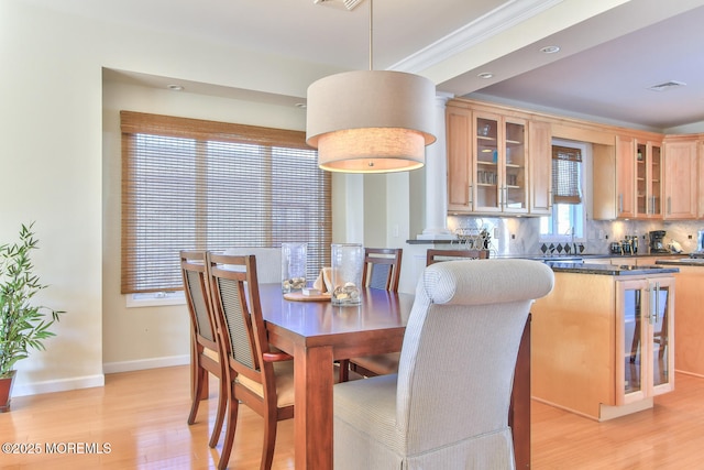 dining room featuring light wood-type flooring, baseboards, and ornamental molding