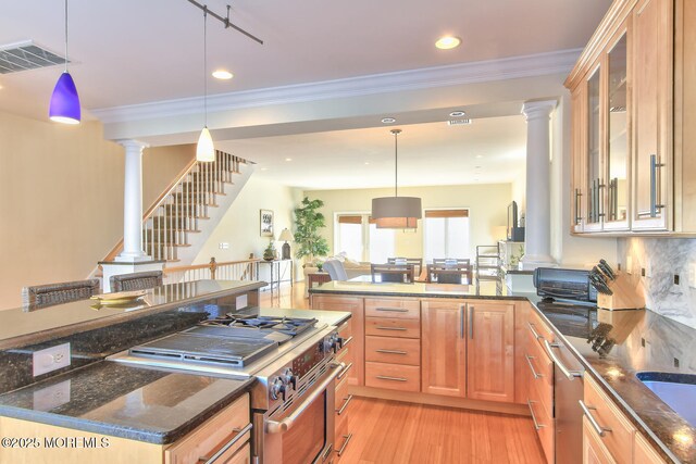 kitchen featuring stainless steel appliances, ornate columns, light wood-style floors, dark stone counters, and recessed lighting