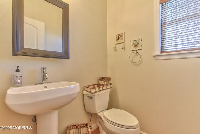 bathroom with baseboards, toilet, and a sink