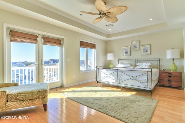 bedroom featuring access to exterior, light wood-style floors, a tray ceiling, ornamental molding, and ceiling fan