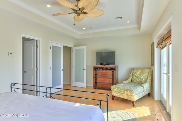 bedroom with light wood finished floors, crown molding, a raised ceiling, recessed lighting, and a ceiling fan