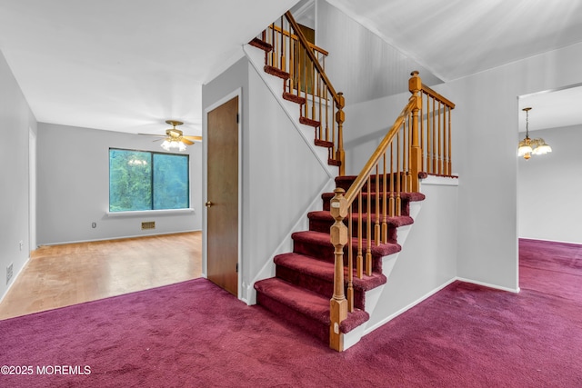staircase featuring carpet, ceiling fan, a chandelier, and baseboards